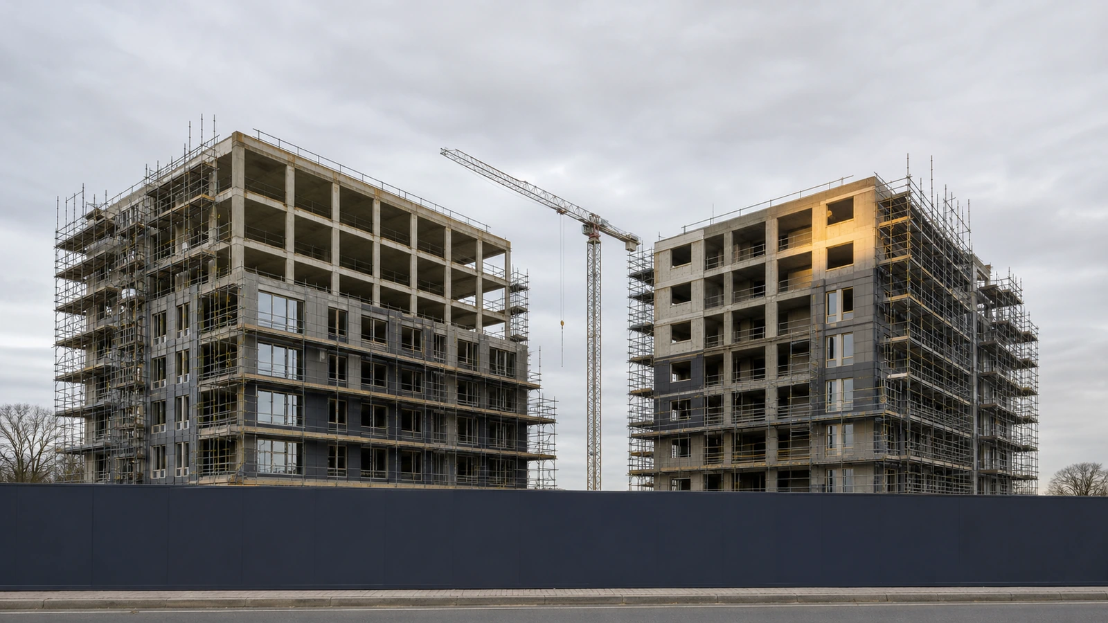 Mid-construction residential apartment blocks with scaffolding under an overcast sky